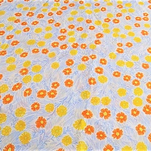 May include: A white fabric with a repeating pattern of yellow and orange flowers. The flowers are stylized and have a simple design.