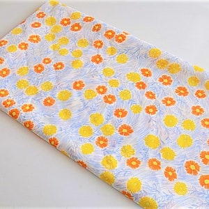 May include: White fabric with a repeating pattern of small orange and yellow flowers on a white background.