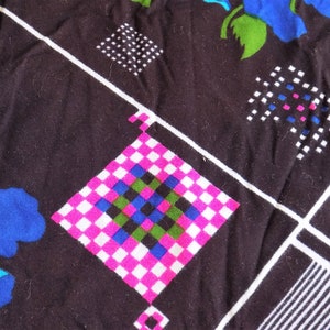 May include: Black fabric with a white, pink, blue, and green checkered pattern. The fabric also has a white and black geometric pattern and a blue flower.