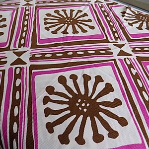 Puede incluir: Tela blanca con un patr&oacute;n repetido de formas geom&eacute;tricas marrones y rosas y flores estilizadas. La tela tiene una superficie texturizada.