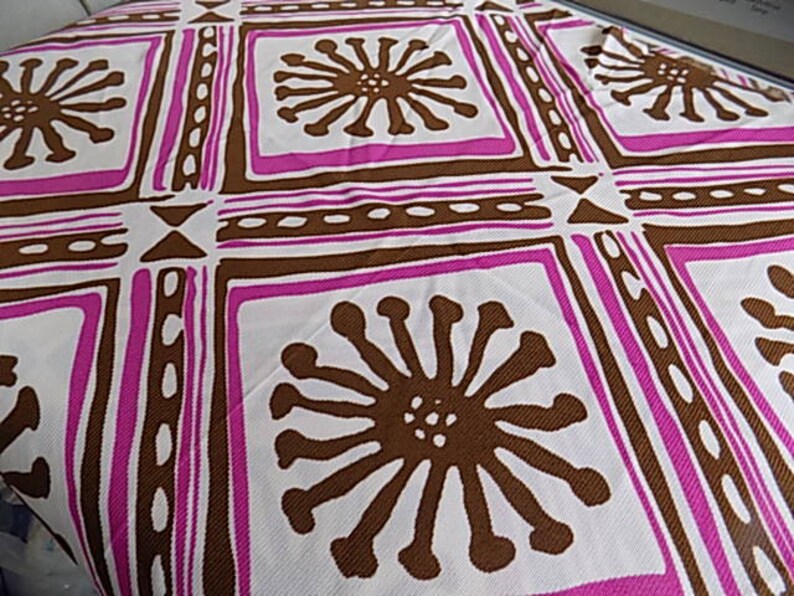 Puede incluir: Tela blanca con un patr&oacute;n repetido de formas geom&eacute;tricas marrones y rosas y flores estilizadas. La tela tiene una superficie texturizada.