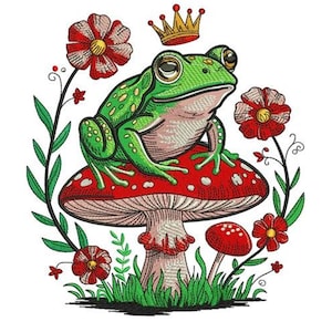 May include: An embroidered design featuring a green frog wearing a gold crown, sitting atop a red mushroom with white spots. Red and white flowers and green foliage surround the frog and mushroom, creating a whimsical, fairytale theme.
