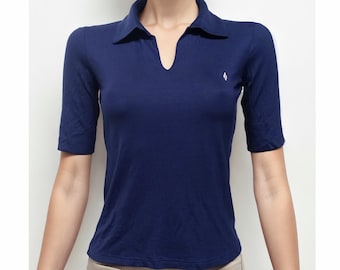 May include: A navy blue short-sleeved polo shirt with a white v-neck and a small white diamond logo on the right side of the chest.