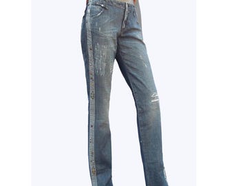 May include: Blue denim jeans featuring a straight-leg cut, a mid-rise waist, and a vertical side panel adorned with small metallic studs. The fabric displays a faded wash with subtle distressed detailing and a classic button and zipper fly closure.