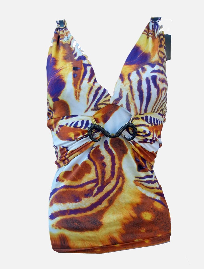Op de afbeelding: Een mouwloze top met een levendig tijgerstrepenpatroon in tinten oranje, geel, wit en donkerpaars. Het kledingstuk heeft een diepe V-hals en een centraal zwart decoratief element dat de stof bij de taille samenbrengt.