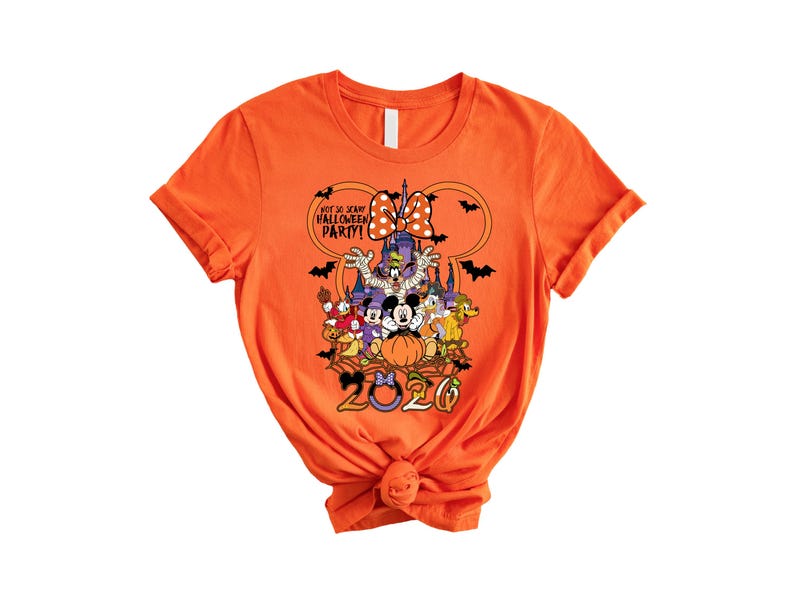 May include: An orange short-sleeve t-shirt featuring a graphic of Disney characters in Halloween costumes, a castle, bats, and the text "NOT SO SCARY HALLOWEEN PARTY!" and "2020" with a Minnie Mouse bow icon above the characters.