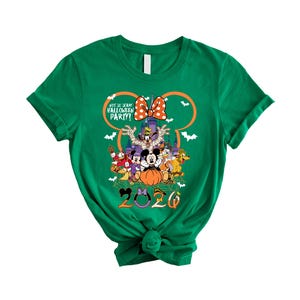 May include: A green short-sleeve t-shirt featuring a graphic of Disney characters in Halloween costumes. The design includes a pumpkin, a castle, bats, and the text "NOT SO SCARY HALLOWEEN PARTY!" with the year "2020" printed at the bottom.
