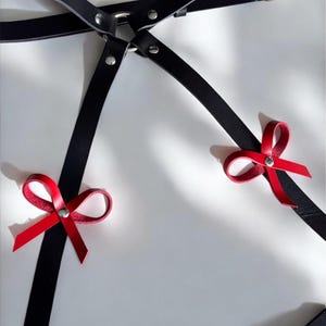 Black leather thigh harness with red bow accents, adjustable straps and silver hardware, back design detail, handmade garter belt for women, edgy fashion accessory