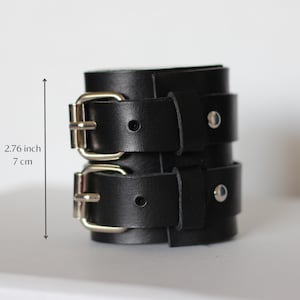 May include: Black leather double buckle bracelet with silver hardware. The bracelet is 2.76 inches in length.