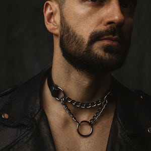 Man wearing black leather chain choker with O-ring – gothic punk fashion jewelry, edgy style necklace.