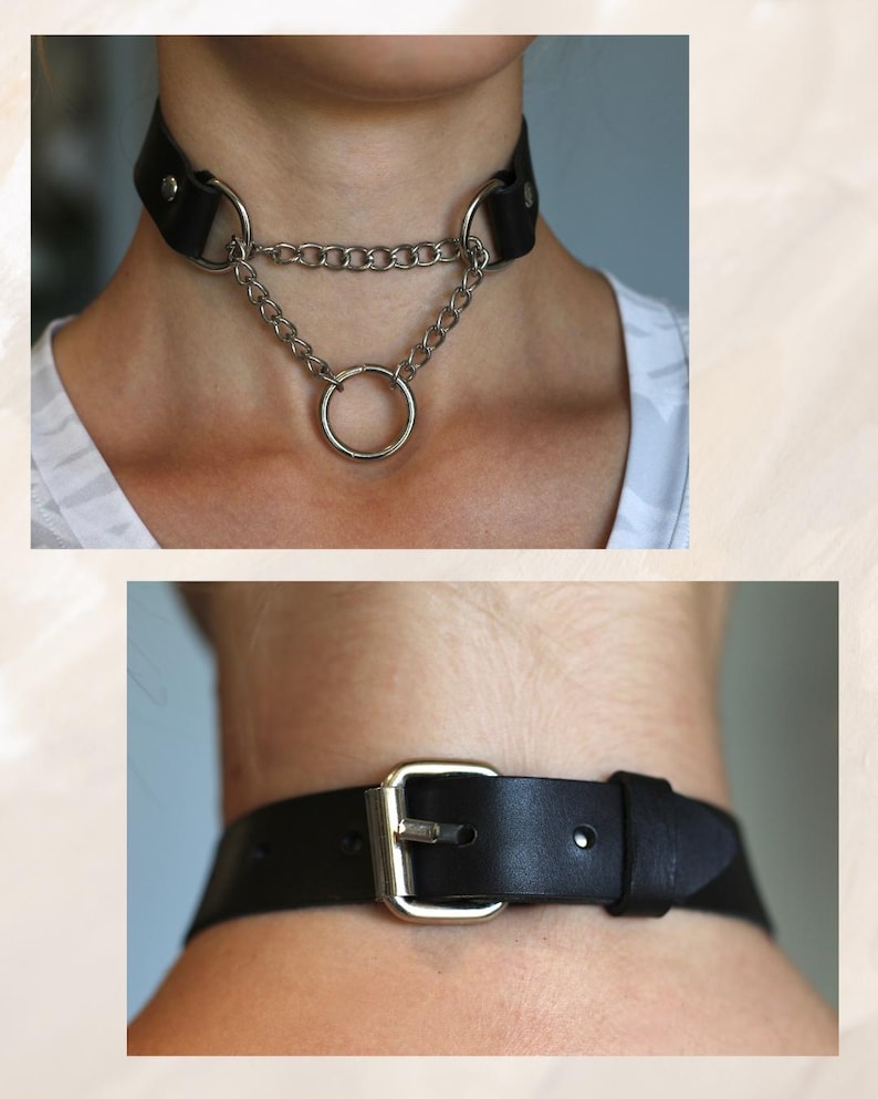 May include: A black leather choker with a silver chain and a large silver ring. The choker has a buckle closure.