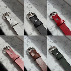 Color options for leather chokers shown on marble background: White, Black, Red, Pink, Brown, Green. Each strap features a silver buckle and visible leather texture.