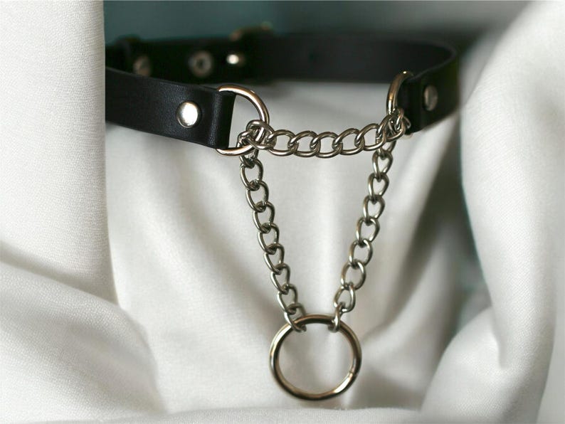Black leather choker with metal chains and a circular ring. Adjustable size, durable metal hardware. A modern and stylish accessory for a unique look.