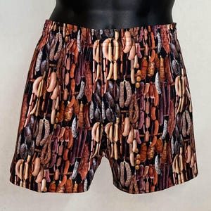 May include: Boxer shorts with an all-over print of various sausages in shades of brown, red, and tan against a black background. The shorts have an elastic waistband.