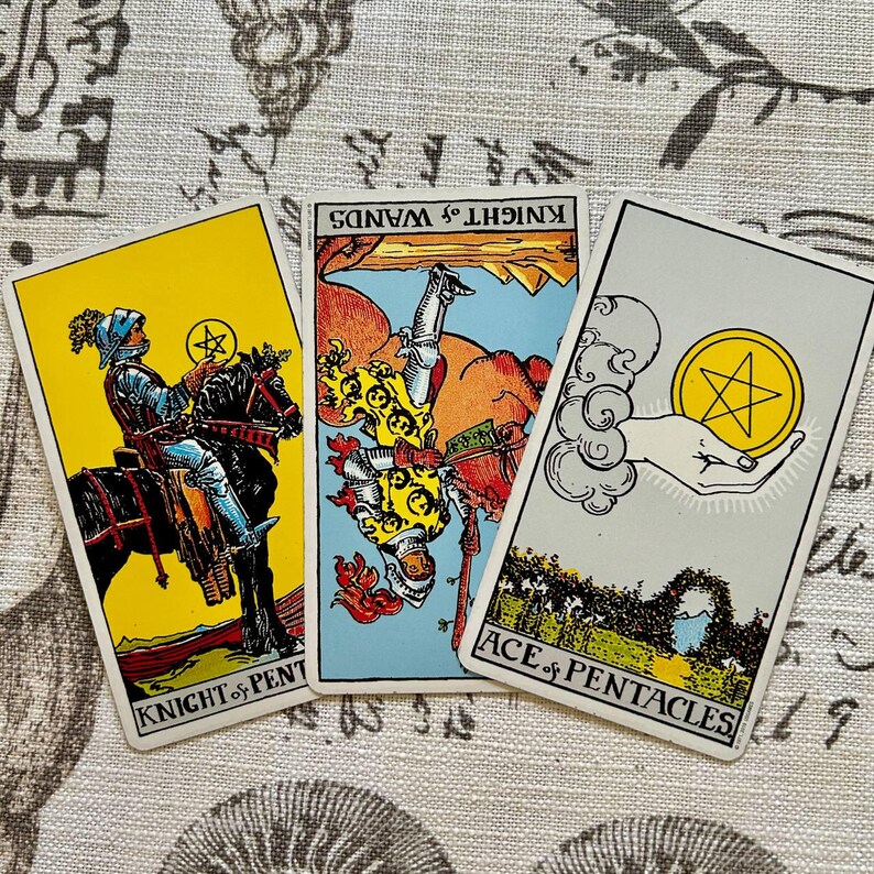 May include: Three tarot cards are displayed, featuring colorful illustrations and text. The cards include "Knight of Pentacles," "Knight of Wands," and "Ace of Pentacles." The cards have a vintage aesthetic, with detailed artwork and bold colors.
