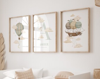 May include: Three framed prints with a nursery theme. The prints feature illustrations of hot air balloons and clouds in a light blue and brown color scheme. The middle print has the name "ASHER" in a light blue font.