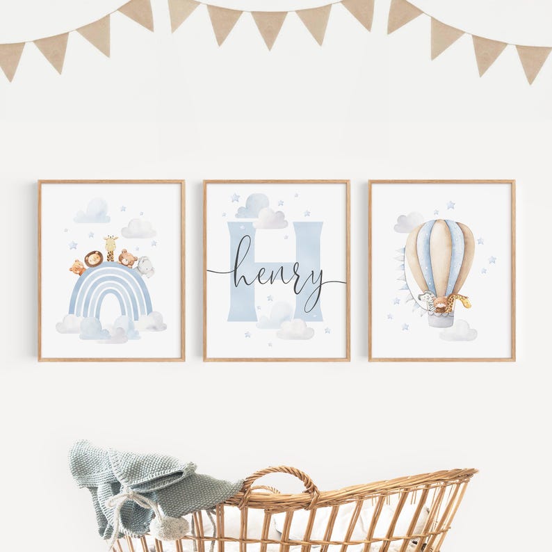 May include: Three framed nursery art prints. The prints feature a blue rainbow with animals, the name "Henry" with a blue "H", and a hot air balloon with a giraffe. The art has a watercolor style with a light blue and tan color palette.