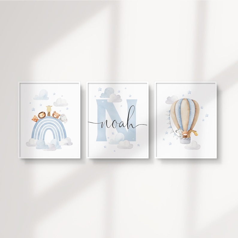 May include: Three framed watercolor prints with a nursery theme. One print features a rainbow with animals, another has the name "Noah" with a large "N", and the third shows a hot air balloon with a giraffe.