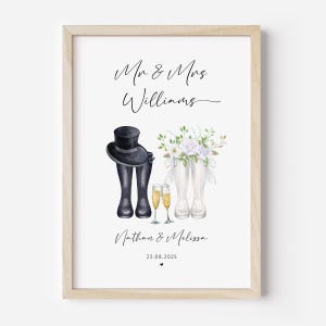 Könnte beinhalten: Ein gerahmter Druck mit Aquarellillustrationen von Hochzeitselementen. Er zeigt einen Zylinder und schwarze Stiefel, weiße Stiefel mit Blumen, Sektgläser und die Namen "Nathan & Melissa" mit einem Datum. Der Text "Mr & Mrs Williams" ist ebenfalls vorhanden.
