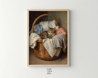 Op de afbeelding: Een ingelijste print van een lapjeskat die rust in een rieten mand gevuld met gevouwen wasgoed. Het wasgoed omvat witte, blauwe en roze stoffen. De mand heeft een gebogen handvat en staat tegen een gedempte achtergrond.