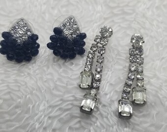 May include: A pair of dangle earrings with clear rhinestones and a pair of stud earrings with black and clear rhinestones.