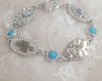 May include: A silver bracelet with turquoise stones and cactus charms. The bracelet has a lobster clasp closure.