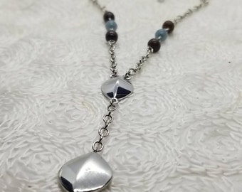 May include: A silver necklace with a chain and two silver pendant charms. The necklace is decorated with brown and blue beads.