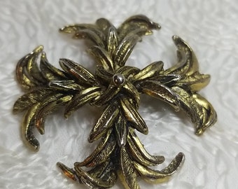 May include: A gold and silver tone brooch with a floral design. The brooch is made of metal and has a detailed design of leaves and flowers.