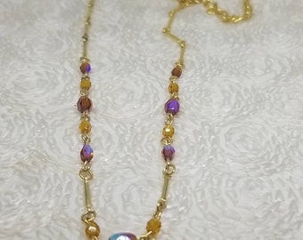 May include: A gold chain necklace with iridescent purple and amber glass beads.