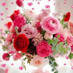 Puede incluir: Un ramo de flores rosas, rojas y blancas en un jarrón de vidrio transparente con una base rosa. El jarrón está sobre una superficie blanca con una caja de regalo rosa y blanca en el fondo. El texto "Happy Birthday" está escrito en letras rosas sobre las flores.