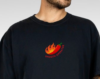 May include: A black t-shirt featuring a red chilli pepper graphic and the text "Smooth Operator" printed on the front.