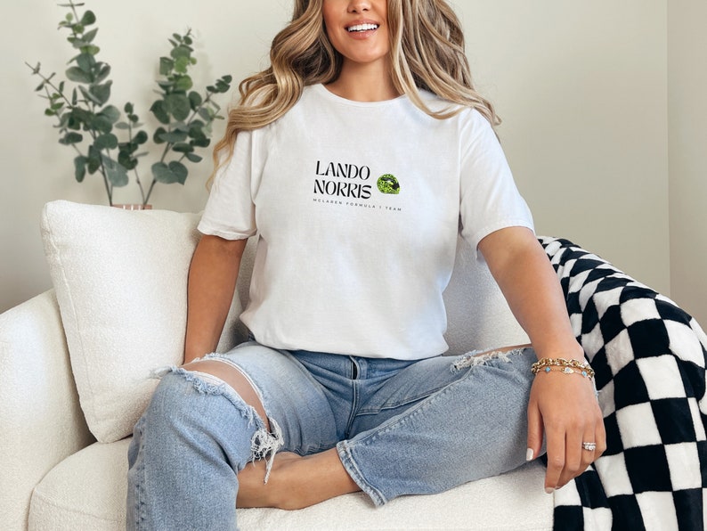 May include: A white t-shirt with a black graphic print that says "Lando Norris McLaren Formula 1 Team" with a green and black logo.