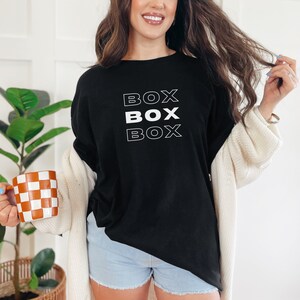 May include: A black long-sleeved shirt with the word "BOX" repeated three times in white outlined text.