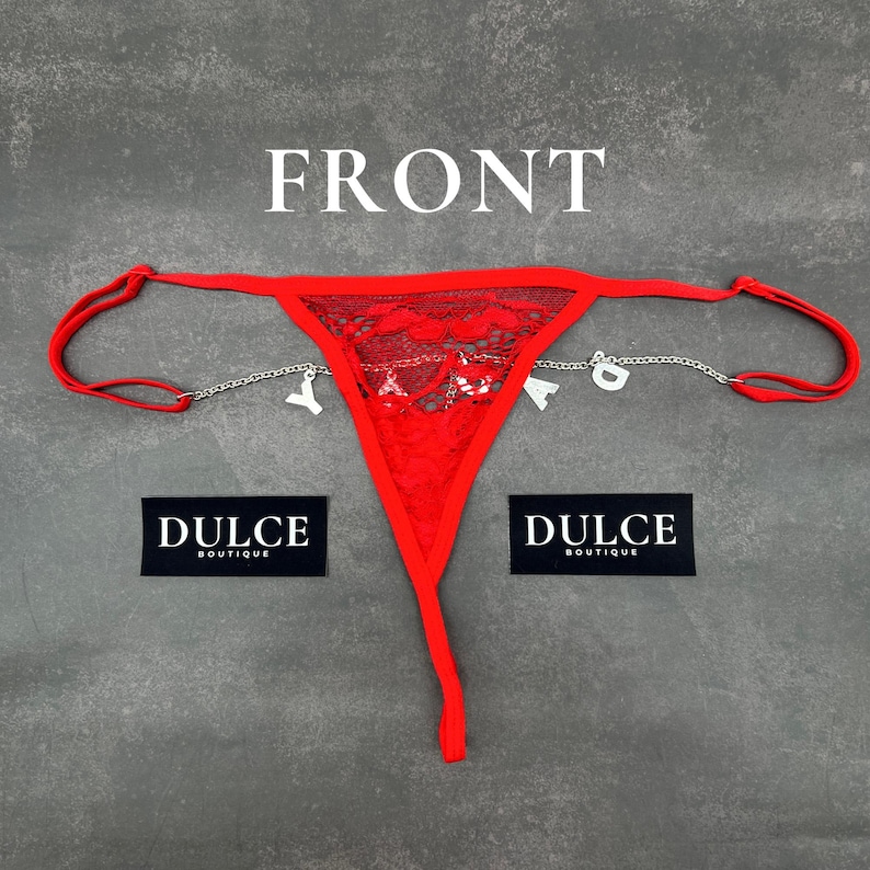 Puede incluir: Lingerie de encaje roja con una cadena plateada y abalorios que deletrean "DULCE". La lencer&iacute;a es de la marca "DULCE BOUTIQUE".