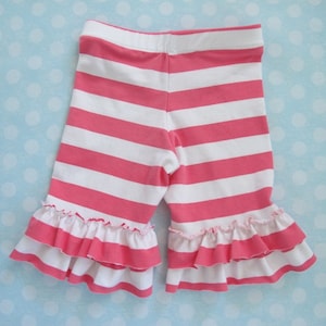 Puede incluir: Leggings de rayas rosas y blancas con un doble ribete de volantes. Los leggings están hechos de una tela suave y elástica.