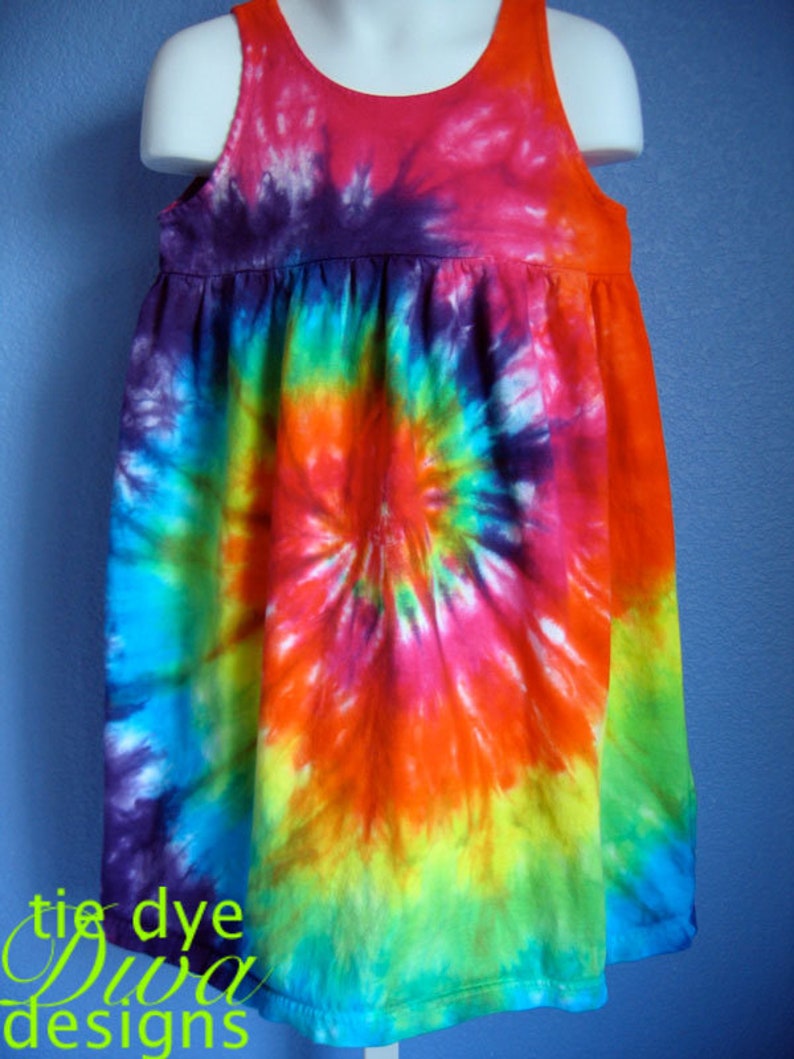 May include: A colorful tie-dye dress with a spiral pattern in shades of blue, green, yellow, orange, pink, and purple. The dress has a sleeveless design and a scoop neckline.
