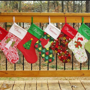 May include: Six personalised Christmas stockings with different designs and names embroidered on them. The stockings are hung on a wooden railing. The names on the stockings are Chris, Phillip, Vanessa, Matthew, and Karla.