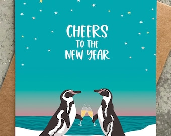 May include: A teal blue greeting card with a white background features two penguins toasting with champagne glasses. The card has a starry sky background and the text "CHEERS TO THE NEW YEAR".