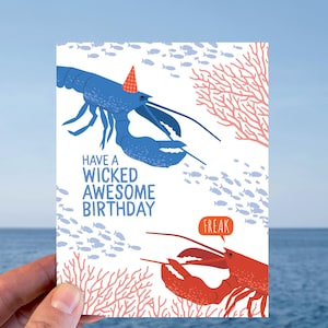 May include: A birthday card featuring two cartoon lobsters. One blue lobster wears a party hat, and the other red lobster has a speech bubble that says "FREAK". The card has the text "HAVE A WICKED AWESOME BIRTHDAY".