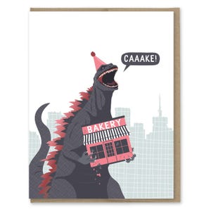 May include: A greeting card featuring a grey monster wearing a pink party hat, holding a pink bakery building with a black and white striped awning. The monster has red dorsal fins and a speech bubble that says CAAAKE! against a city skyline.