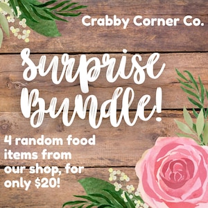 May include: A wooden background with the text "Surprise Bundle!" in white script. The image also includes the text "4 random food items from our shop". A pink rose and green foliage decorate the image.
