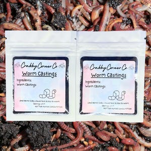 May include: Two small white bags with black labels that say "Crabby Corner Co. Worm Castings" and list the ingredients as "Worm Castings". The bags are filled with dark brown worm castings. The labels also state "Land Hermit Crabs should have access to worm castings 24/7" and "NOT FOR HUMAN CONSUMPTION".