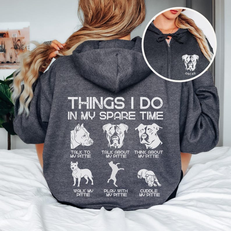 May include: A gray hooded sweatshirt with a white graphic on the back that says "Things I do in my spare time" and shows a series of illustrations of pit bull dogs with text describing activities like "Talk to my pittie", "Walk my pittie", and "Cuddle my pittie". The back of the hood has a white pit bull illustration and the name "Oscar" in white text.