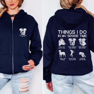 May include: A navy blue zippered hoodie with a white graphic on the front that says "Pittie Mom" and a white graphic on the back that says "Things I do in my spare time" with a list of activities involving a pit bull dog.