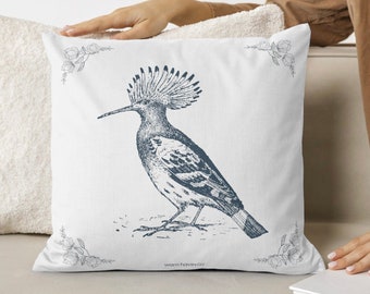 May include: A white throw pillow with a blue and white illustration of a hoopoe bird. The pillow has a white background with a blue border and floral accents.