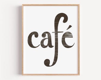May include: A framed print with the word "café" in a dark brown, distressed font against a white background. The wooden frame adds a natural touch to the artwork, suitable for kitchen or dining room decor.