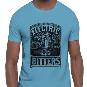 May include: A light blue t-shirt with a black graphic of a vintage label that reads "Electric Bitters".