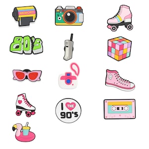 May include: A collection of colorful 80s and 90s themed accessories. Includes a film roll, camera, roller skates, a Rubik's cube, sunglasses, a camera, a high-top sneaker, a roller skate, a pin that says "I love the 90's", a cassette tape, and a flamingo float.