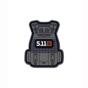 以下が含まれることがあります： グレーの戦術用ベストパッチで、5.11のロゴと「5.11」という文字が白で書かれています。