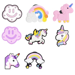 Könnte beinhalten: Eine Sammlung bunter Schuhanhänger mit rosa Einhörnern, Regenbogen und Wolkenmotiven. Die Anhänger sind aus Gummi und haben einen schwarzen Rand. Die Einhorn-Anhänger haben ein Horn und eine Mähne. Die Regenbogen-Anhänger haben eine Wolkenbasis.